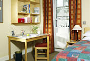 Photograph of a bedroom with a bed, desk and chair