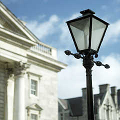 Photograph of a black street lamp to the right of a grey building