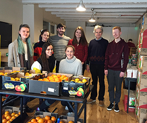 Brian O'Malley with Trinity Vincent de Paul volunteers posing behind tables with crates of fruit.