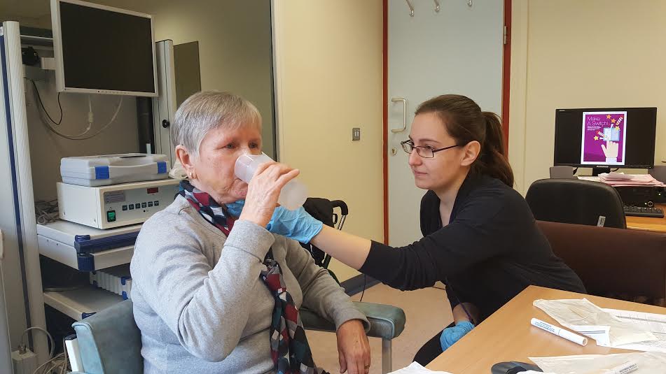 old lady holding water with a nurse