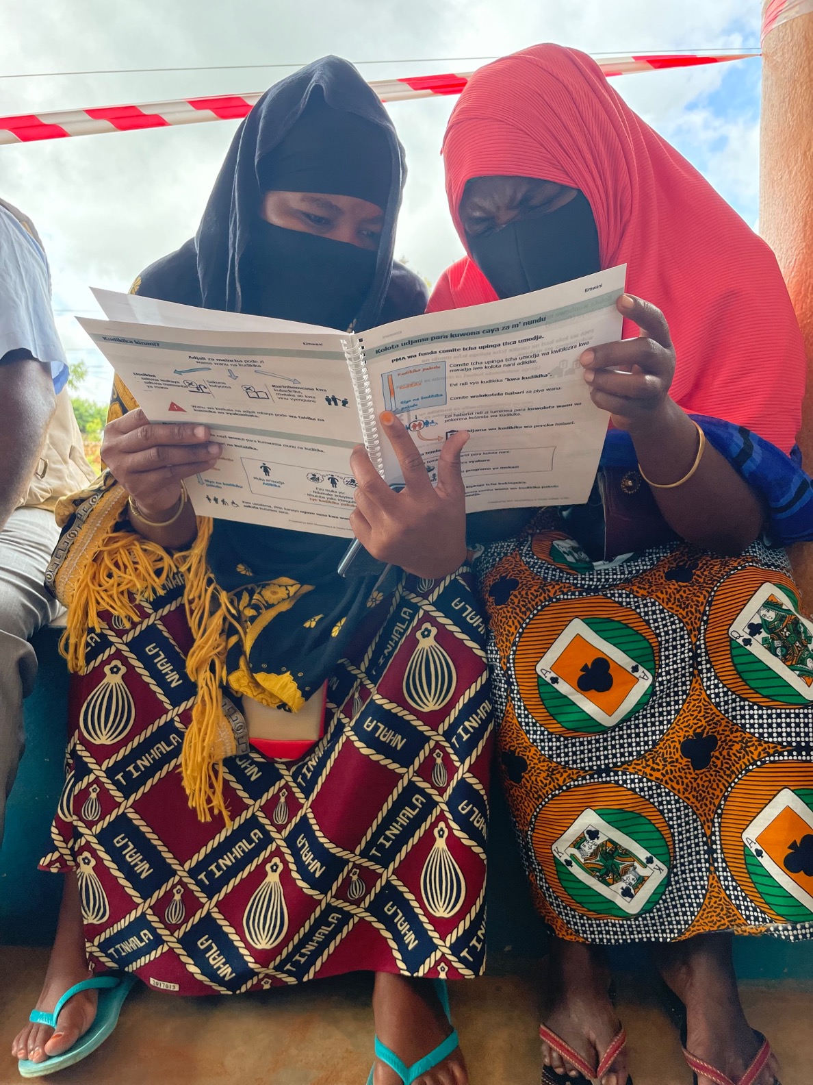 Women looking at communication accessible materials in Mozambique